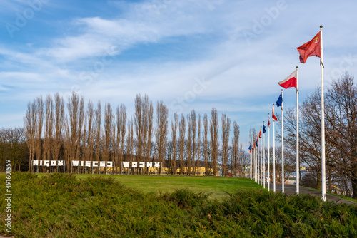 Masts with flags of Poland and European Union. Inscription: Nigdy wiecej wojny (in English: No more war) in background. Gdansk Westerplatte, Poland