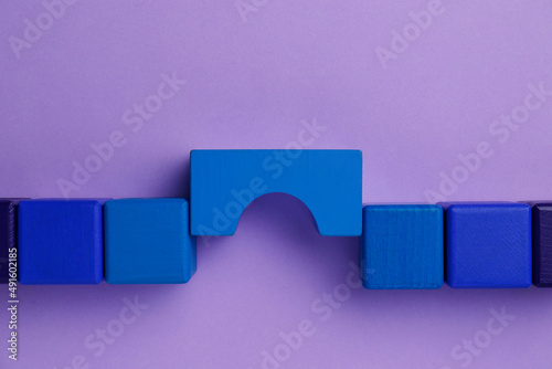 Bridge made of colorful blocks on violet background, flat lay. Connection, relationships and deal concept photo