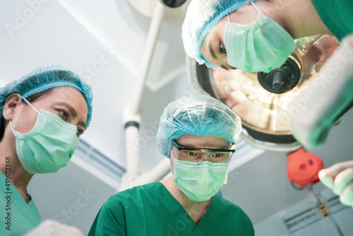 Low Angle Shot of Professional surgeons team performing surgery in operating room, surgeon, Assistants, and Nurses Performing Surgery on a Patient, health care cancer and disease treatment concept