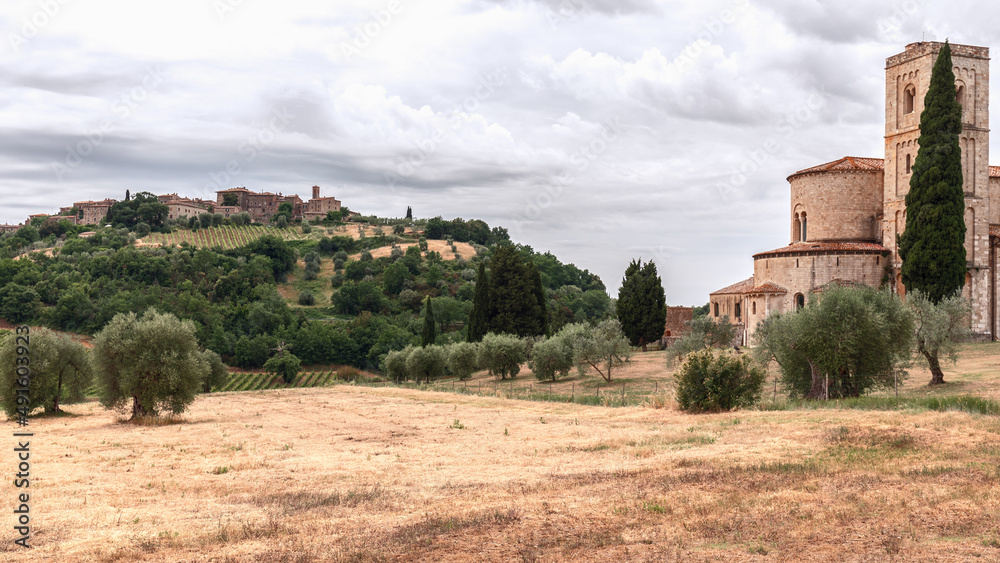 Abbey Sant Antimo, in a lowland among olive trees and cypresses, and on a hilltop a town Castelnuovo dell'Abate, Val d’Orcia, Italy Abbey Sant Antimo, in a lowland among olive trees and cypresses, and on a hilltop a town Castelnuovo dell'Abate, Val d’Orcia, Italy