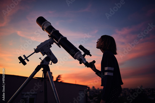 Obraz na płótnie Girl with astronomical telescope stargazing under twilight sky. w salonie