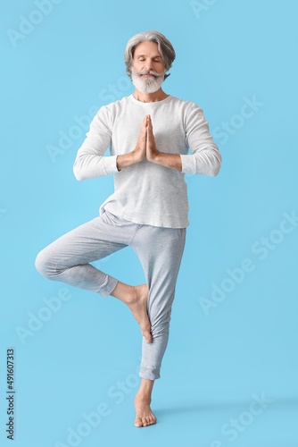 Mature man practicing yoga on color background