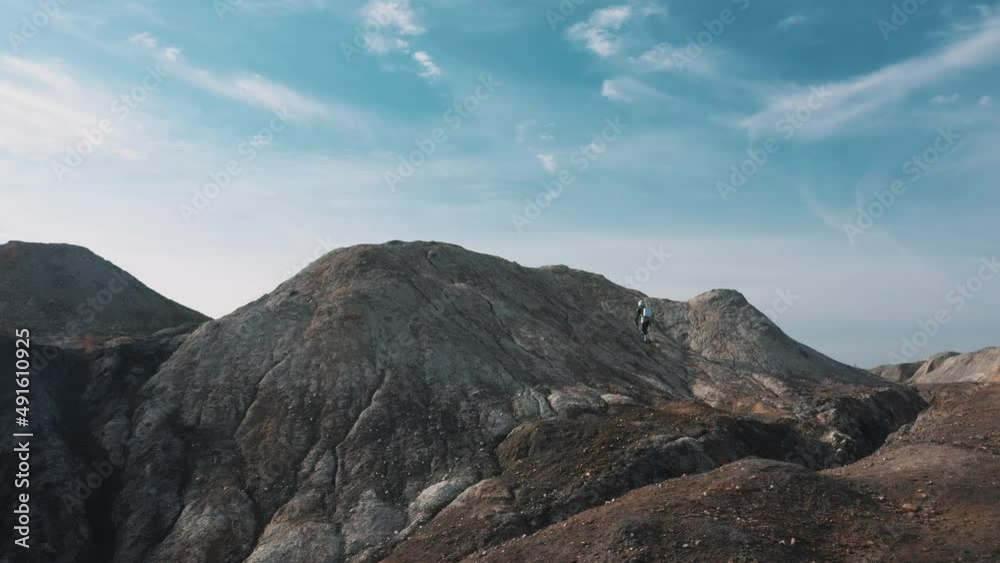 an astronaut climbs a hill from a drone that looks like mars an astronaut climbs a hill from a drone that looks like mars