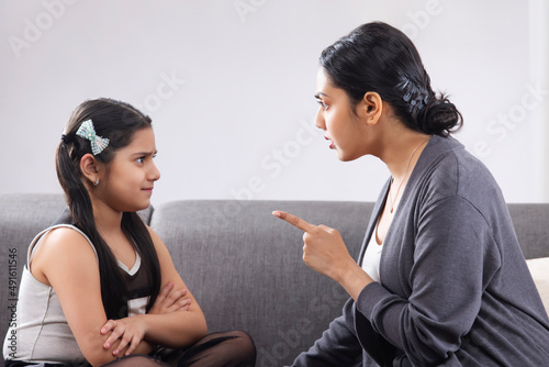 Mother scolding her daughter by showing finger at home