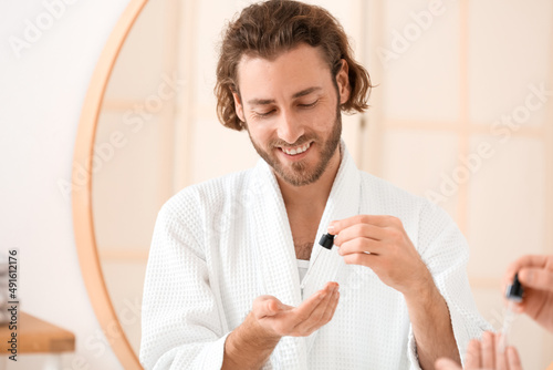 Young man using serum for s...