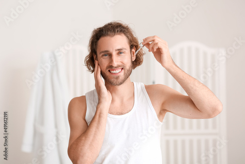 Young man using serum for s...
