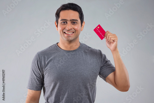 Portrait of happy young man showing credit card photo