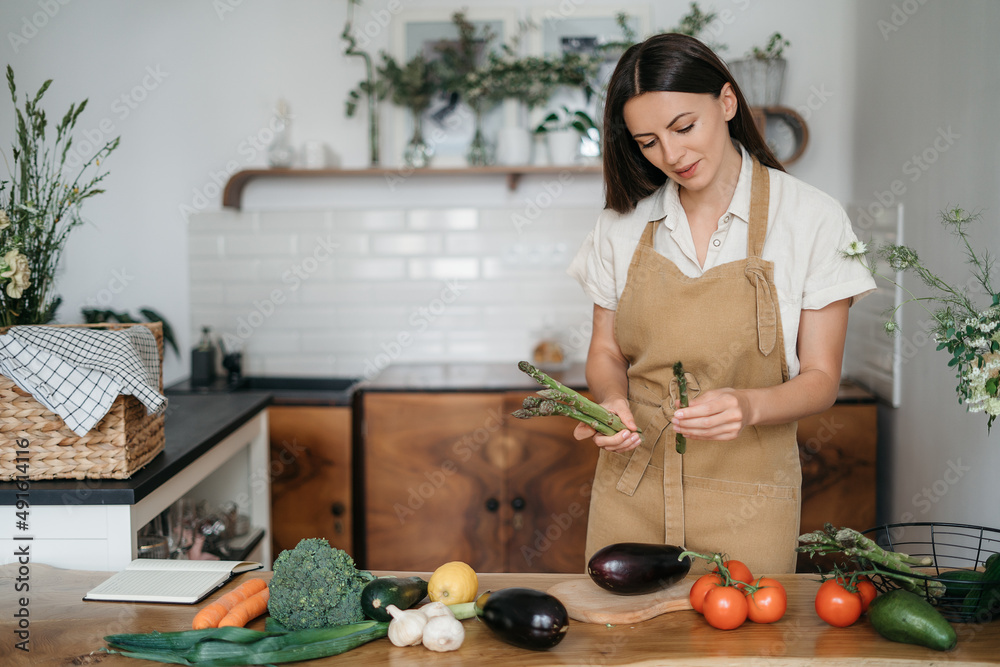 Young Woman Cooking in the kitchen at home. Healthy Food. Diet. Dieting Concept. Healthy Lifestyle. Cooking At Home. Prepare Food.A woman holding fresh organic vegetables in her hands