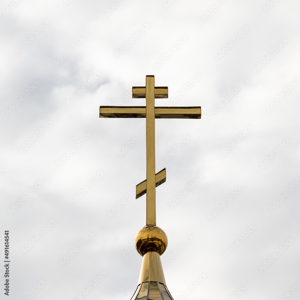 Square photo of an Orthodox cross in cloudy weather against the sky. Square photo of an Orthodox cross in cloudy weather against the sky.