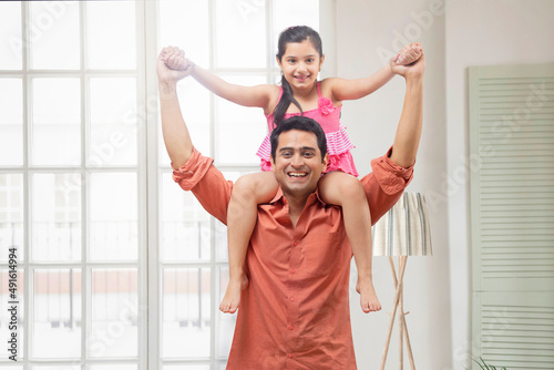 Father carrying daughter on his shoulder in living room