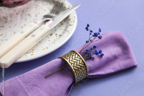 Simple table setting with flowers on purple background, closeup
