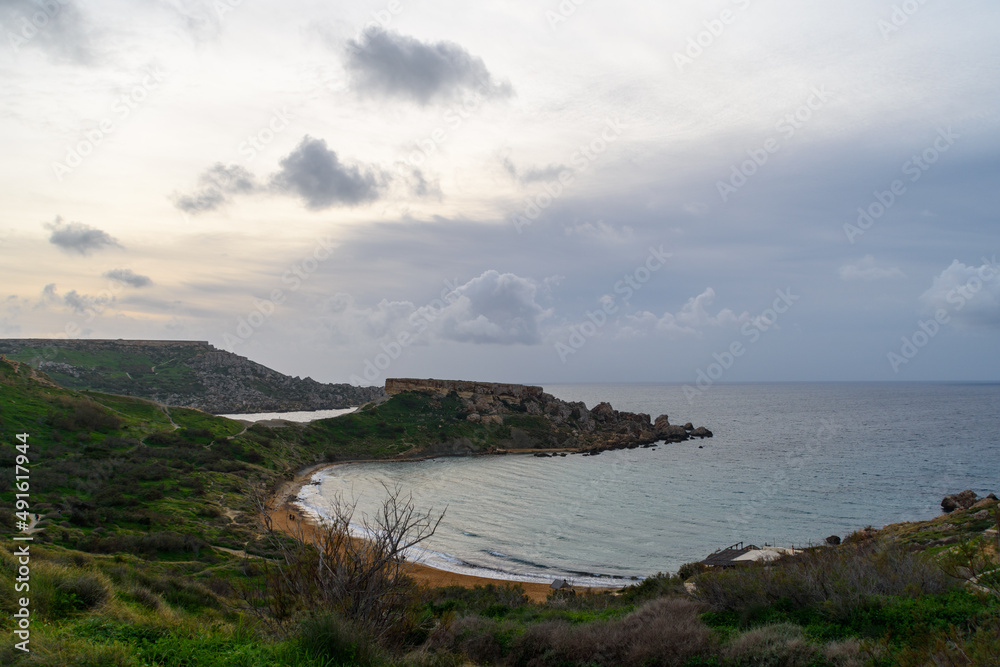 Looking down at the beach at Ghajn Tuffieha Bay in Mgarr, Malta. The Il-Qarraba promontory in the background separates the neighbouring Qarraba Bay.