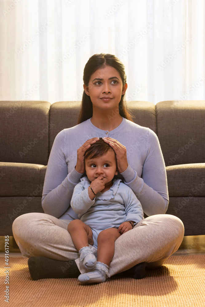 Mother sitting with baby in her lap and looking away