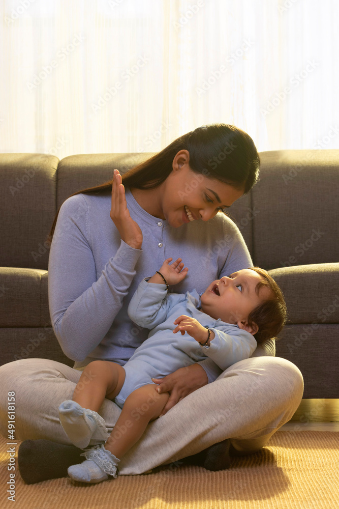 Mother playing with her baby in living room Mother playing with her baby in living room