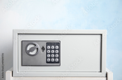Fotografija Closed steel safe on white table against light blue background