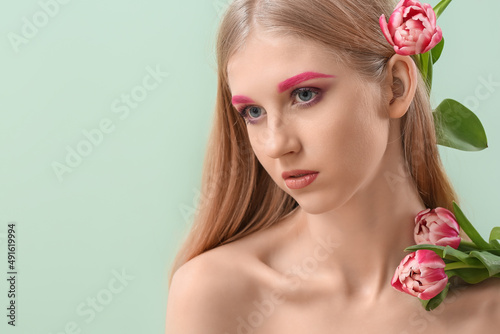 Woman with creative makeup and tulips on green background