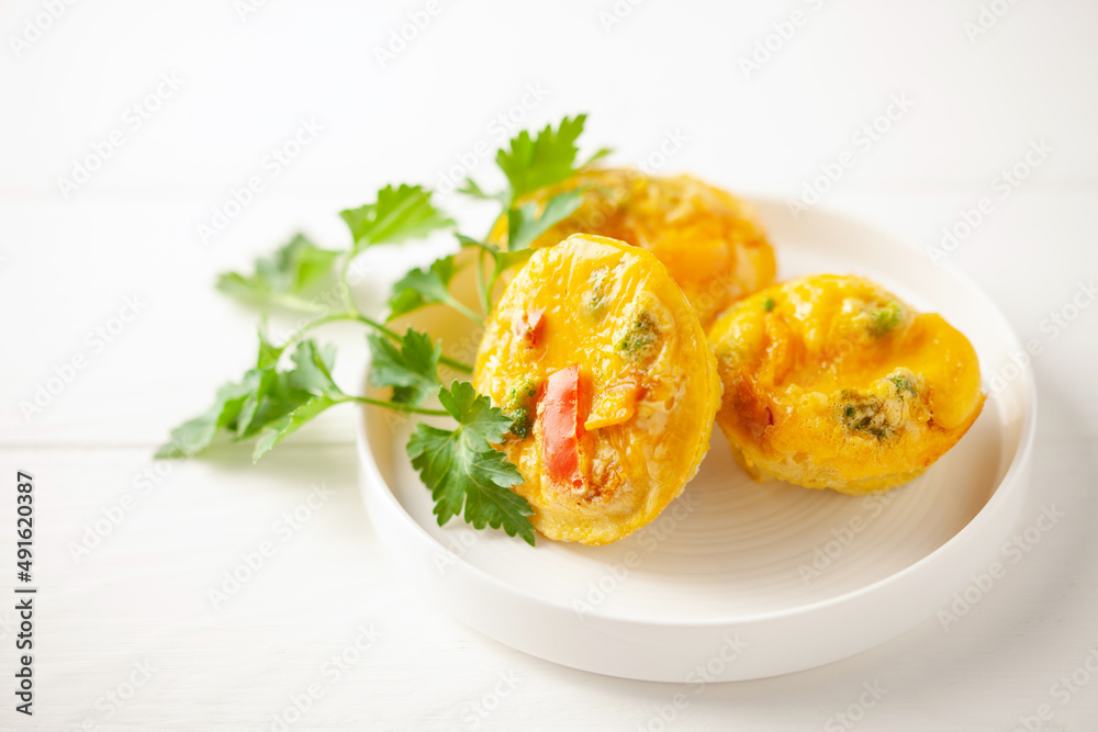Egg muffins ( bites) and parsley leaves in a plate on a gray background. Egg muffins ( bites) and parsley leaves in a plate on a gray background.