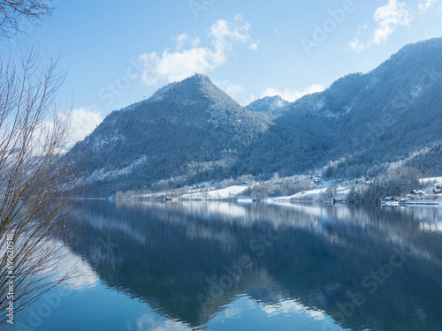 Winter alpine lake Grundlsee. Embedded in the wonderful mountain massif of the Dead Mountains. Clear cold landscape with blue sky and cumulus clouds. Ausserland, Styria, Austria.