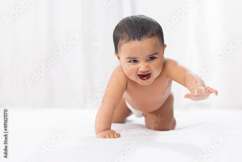 Cute baby in diaper crawling on bed photo