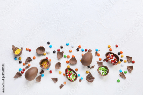 Composition with tasty broken chocolate Easter eggs and candies on light background