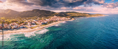 Dramatic panoramic aerial view of iconic Sarti resort town and famous long and empty sandy beach at sunset time with high waves. Vacation on Halkidiki, Greece