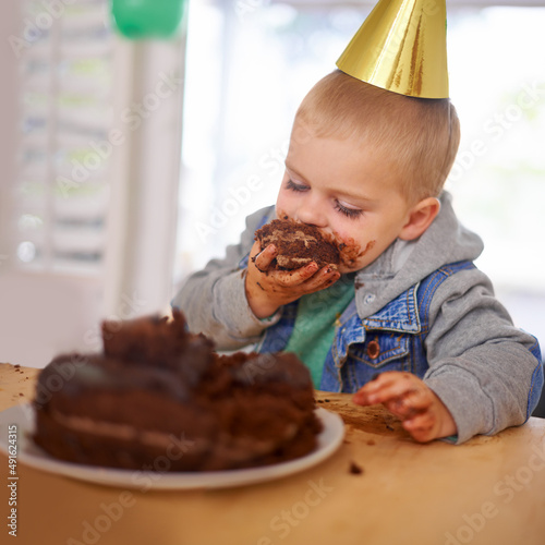 Who left him alone with the cake. Cropped shot of a young boy eating his birthday cake before the party.