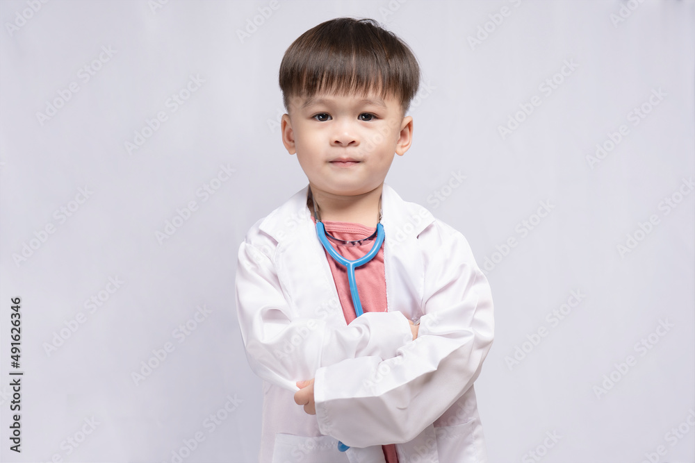 Young cute Asian boy wearing a medical uniform holding a stethoscope playing happy doctor on white background. Preschool children pretend to be a pediatrician. Young cute Asian boy wearing a medical uniform holding a stethoscope playing happy doctor on white background. Preschool children pretend to be a pediatrician.