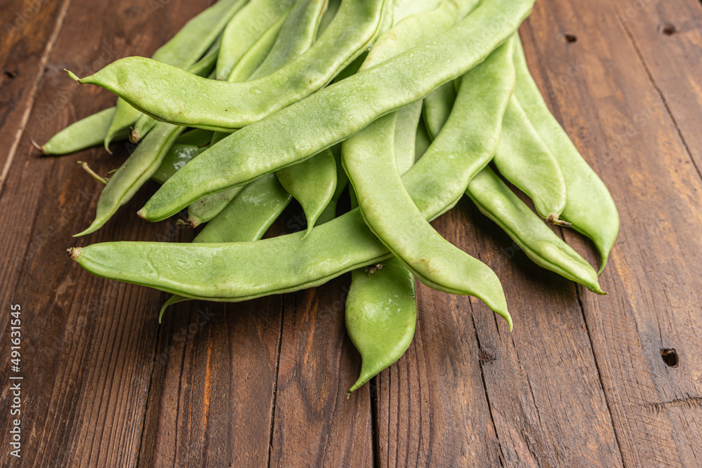 Raw green beans closeup. Fresh green bean also known as french beans, string beans, snap bean, snaps and haricots vert on wooden Raw green beans closeup. Fresh green bean also known as french beans, string beans, snap bean, snaps and haricots vert on wooden
