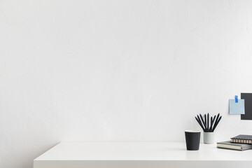 Office table, empty desk with supplies and white wall copy space.	