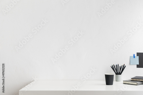 Office table, empty desk with supplies and white wall copy space.	 photo