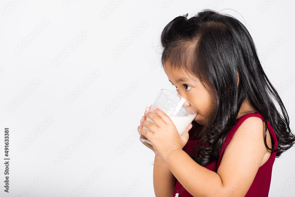 Little cute kid girl 3-4 years old smile holding milk glass he drinking white milk in studio shot isolated on white background, Asian children preschool, Daily life health care Medicine food Little cute kid girl 3-4 years old smile holding milk glass he drinking white milk in studio shot isolated on white background, Asian children preschool, Daily life health care Medicine food