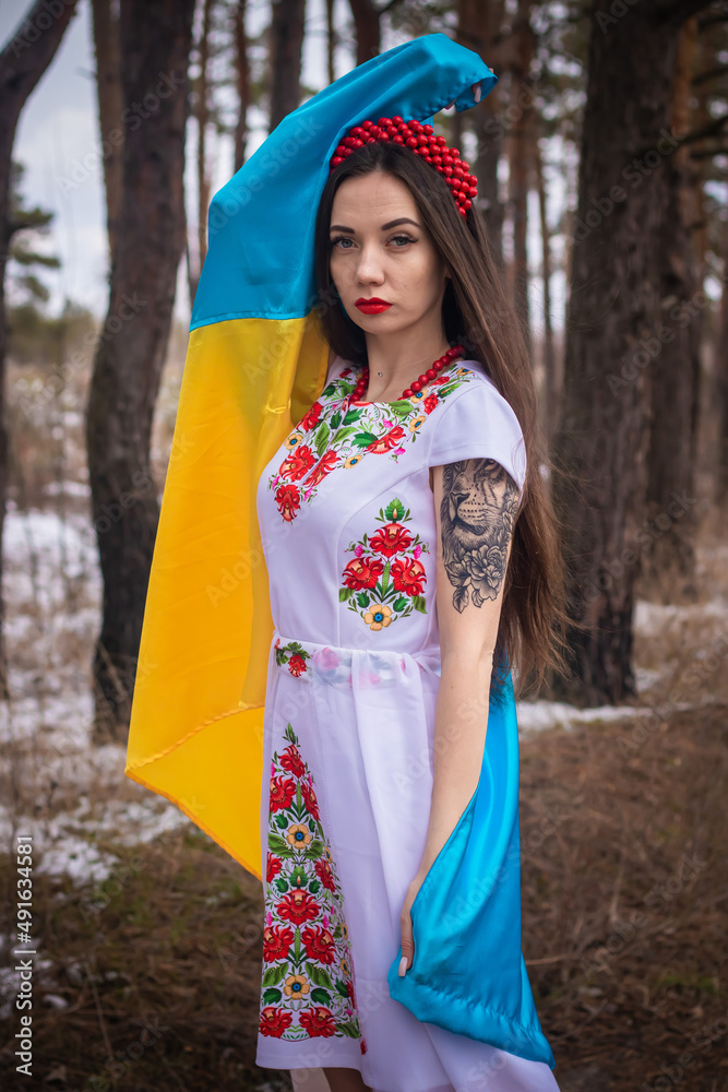 young Ukrainian girl, in traditional Ukrainian dress, embroidery, with the flag of Ukraine in her hands, beads and a wreath on her head, portrait