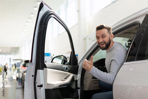 joyful man in a car dealership with a smile on his face in a new SUV © Ivan Traimak