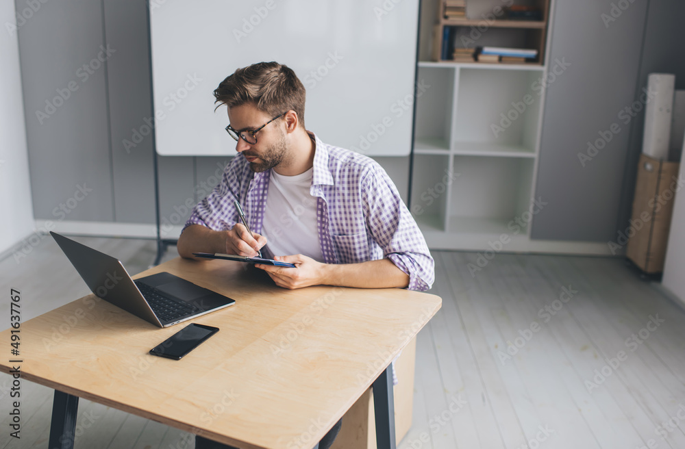 Millennial businessman working at desk in office Millennial businessman working at desk in office