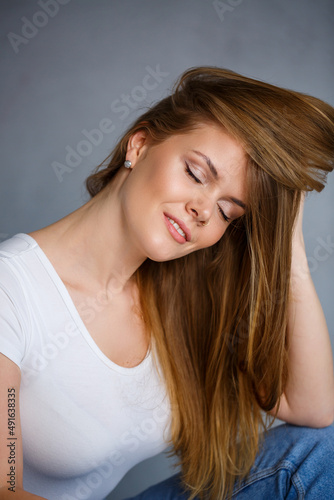 Portrait of a young beautiful woman with blond hair of European appearance. Dressed in a white T-shirt. Emotional photo of a person