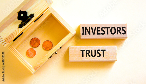 Investors trust symbol. Concept words Investors trust on wooden blocks on a beautiful white table white background. Wooden chest with coins. Business invest and investors trust concept, copy space.