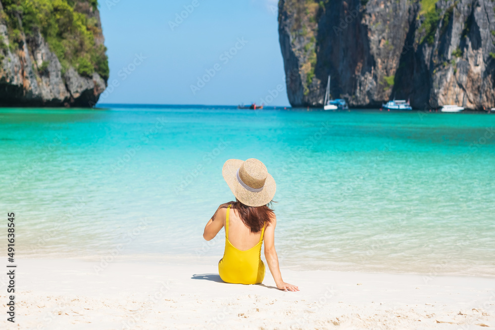 Woman tourist in yellow swimsuit and hat, happy traveller sunbathing at Maya Bay beach on Phi Phi island, Krabi, Thailand. landmark, destination Southeast Asia Travel, vacation and holiday concept Woman tourist in yellow swimsuit and hat, happy traveller sunbathing at Maya Bay beach on Phi Phi island, Krabi, Thailand. landmark, destination Southeast Asia Travel, vacation and holiday concept
