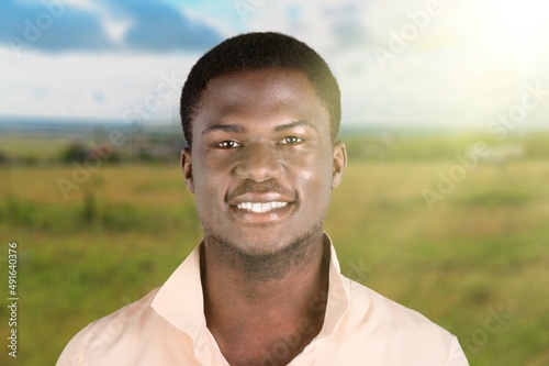 Happy young man smiling in camera on the outdoor background