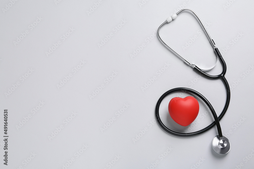 Stethoscope, red decorative heart on grey background, flat lay with space for text. Cardiology concept Stethoscope, red decorative heart on grey background, flat lay with space for text. Cardiology concept