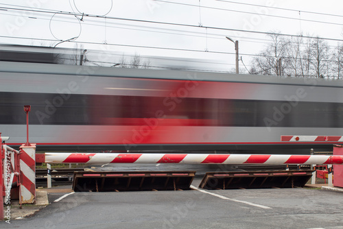 A clear electric train against the background of a closed barrier, road safety.