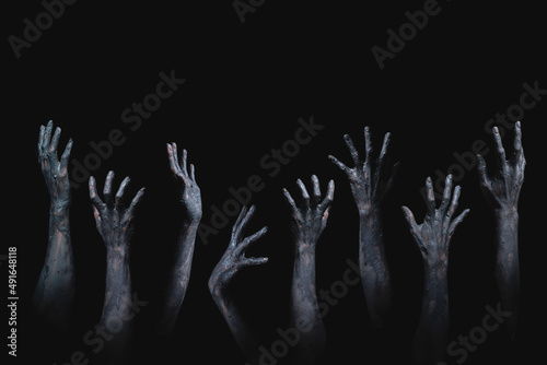 many scary and creepy zombie hands raising from darkness