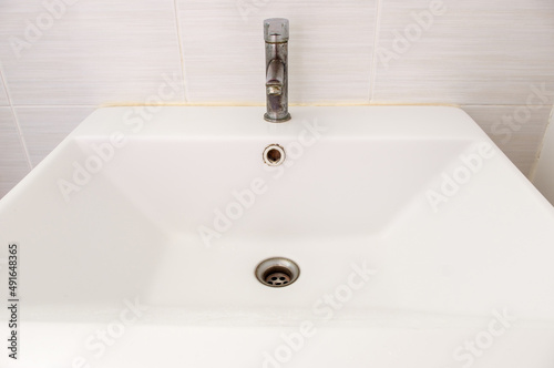 The ceramic sink basin with the stained faucet.
