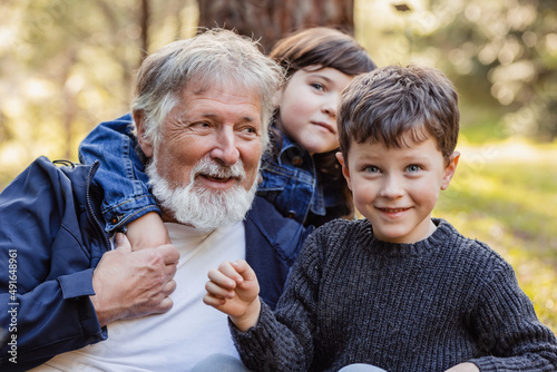 Positive grandfather and kids in forest photo
