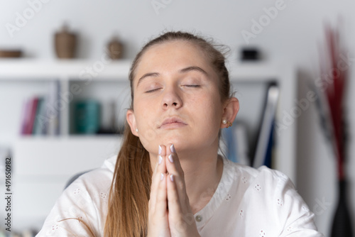 Closeup of blonde woman praying in the office.