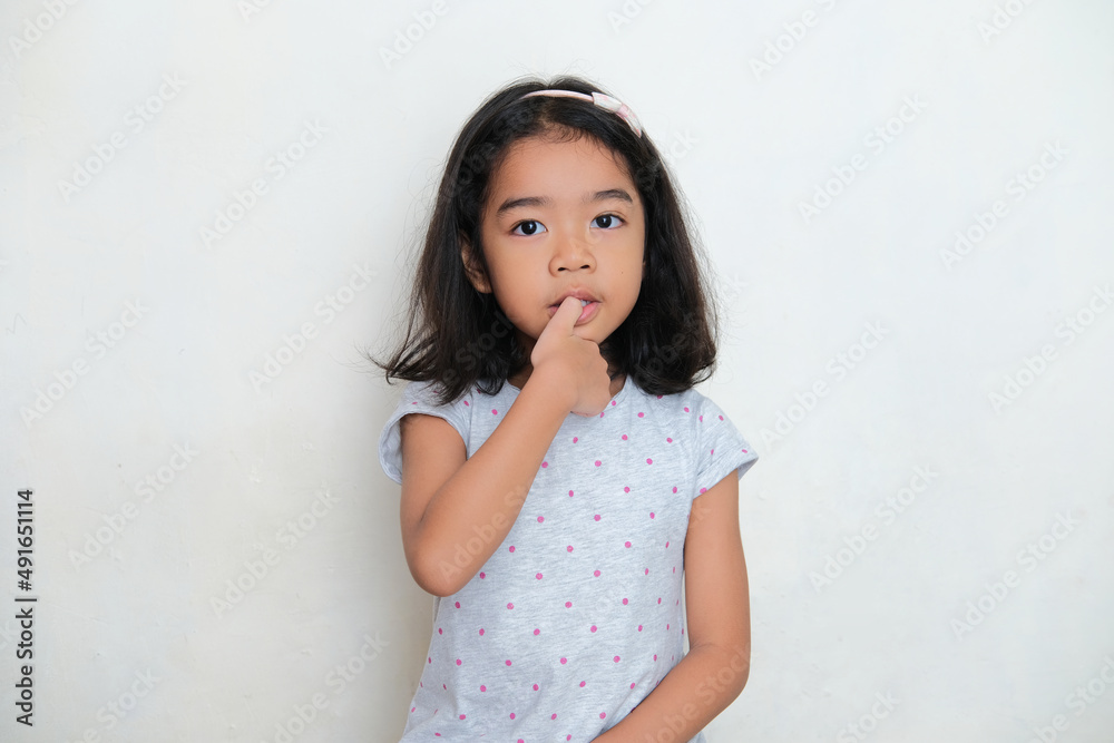Asian kid bitting her thumb finger nail. Bad habit concept Asian kid bitting her thumb finger nail. Bad habit concept