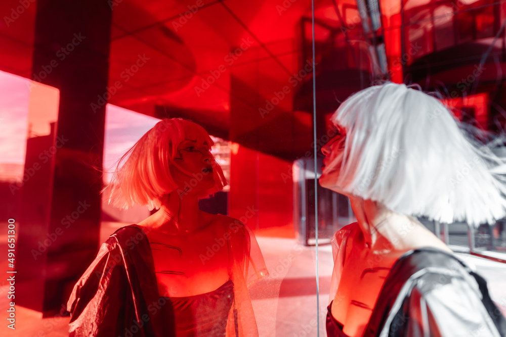 The blonde looks at her reflection in the red mirror. The blonde looks at her reflection in the red mirror.