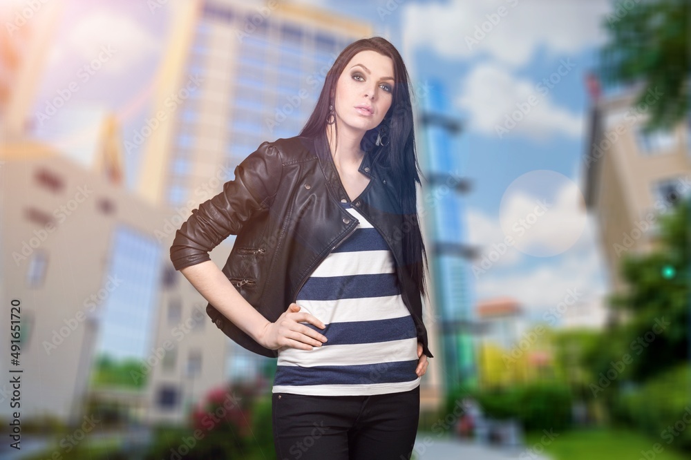Fototapeta premium Happy young woman dressed in casual posing at city enjoys spare time.