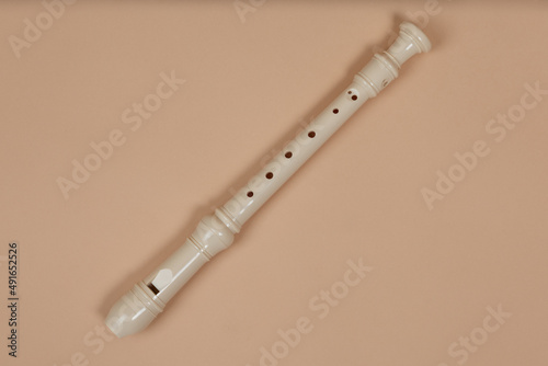 Common fipple flute closeup, beige background. Flute belong to group of woodwind musical instruments. Aerophone or reedless wind instrument that produce sound from flow of air across opening. photo