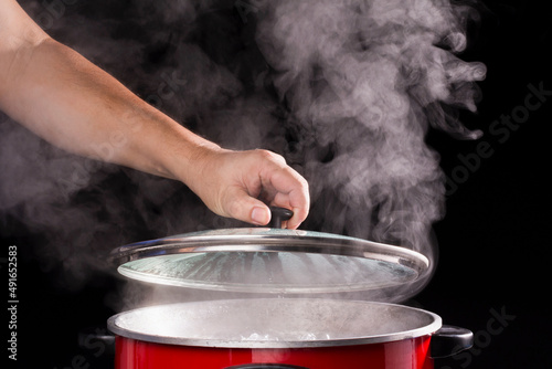 Foto The chef's hand opens the lid of the hot soup pot