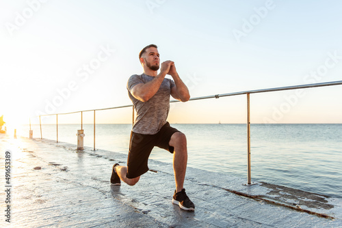 Fotografía Athletic man practicing lunges in the early morning on the beach